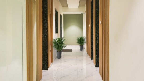 A hallway with a marble floor, green walls, and wooden paneling on the sides. - Hotel Stay Inn near Bhiwandi Thane Railway Station (Bhiwandi)