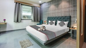 A modern hotel room with a large bed, a bedside table, a nightstand, a window with curtains, and a ceiling fan. - Hotel Stay Inn near Bhiwandi Thane Railway Station (Bhiwandi)
