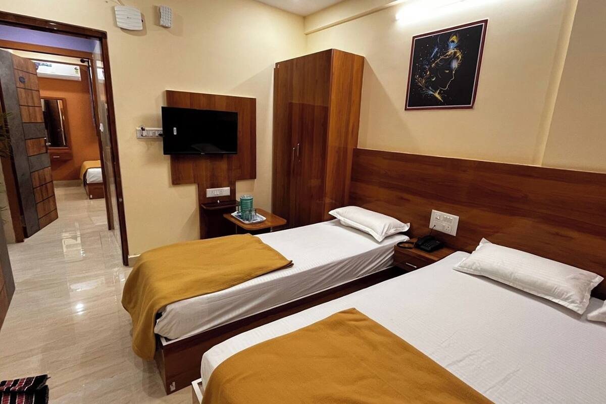 A hotel room with two beds, a wardrobe, a television, and a painting on the wall.