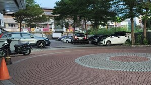 A paved area with a circular pattern, parked cars, and a motorcycle.