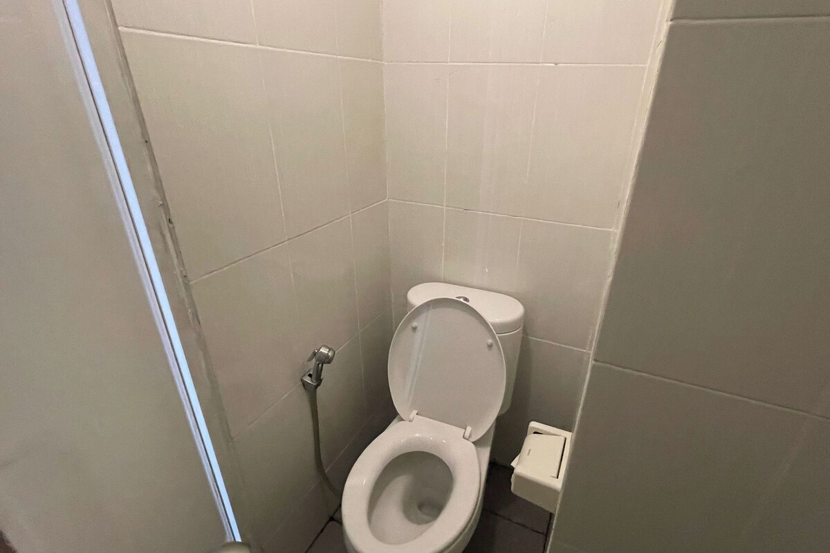 Une petite salle de bain propre, équipée de toilettes, d’un bidet et d’un porte-rouleau de papier toilette.
