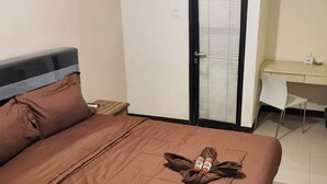 A hotel room with a bed, a desk, and a chair.