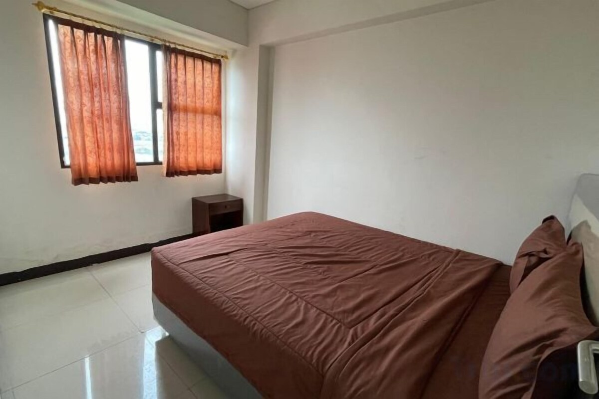 A bedroom with a bed, curtains, a nightstand, and a window.