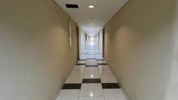 A long, narrow hallway with a checkered floor pattern and white walls.