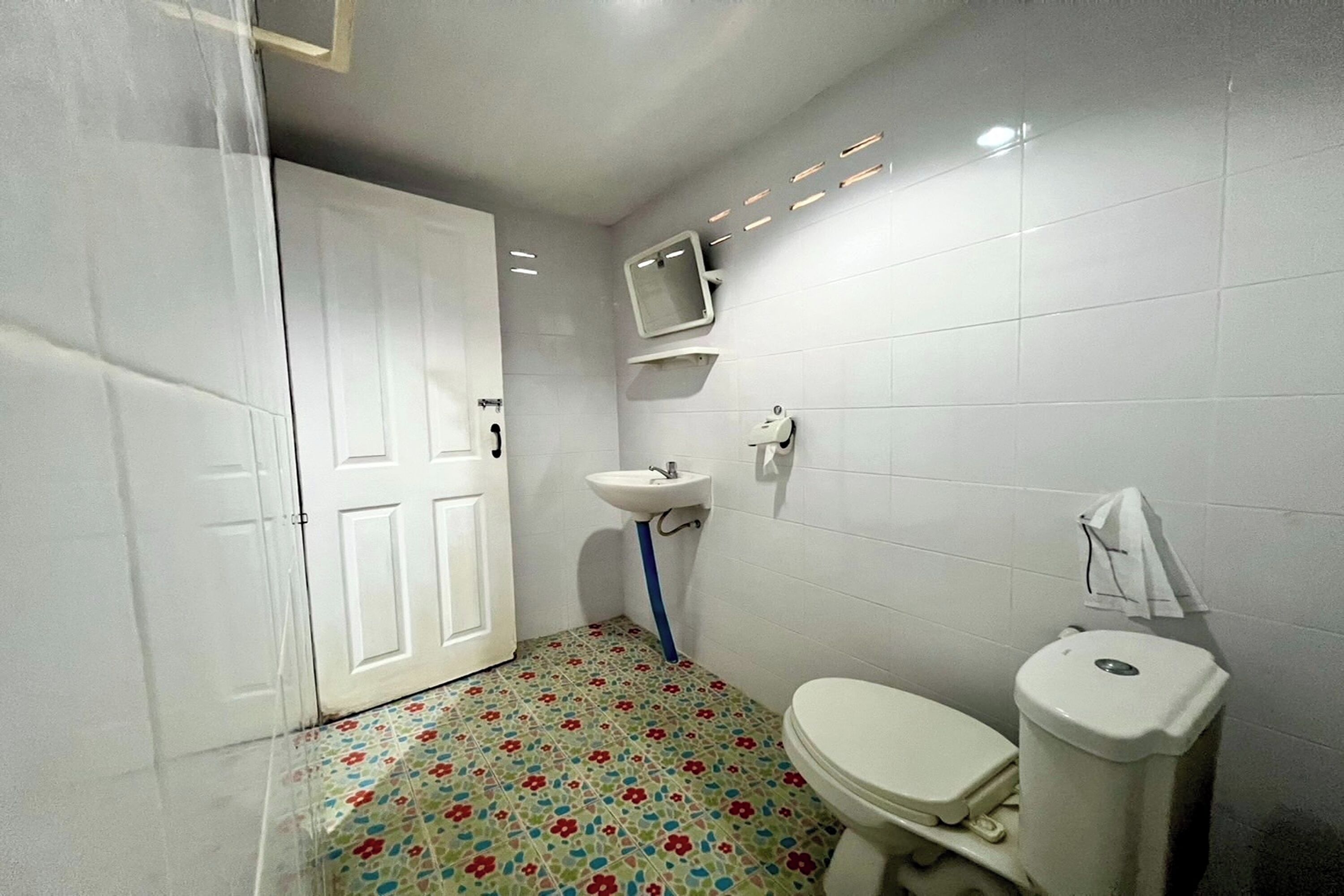 Een kleine badkamer met toilet, wastafel en een spiegel aan de muur.