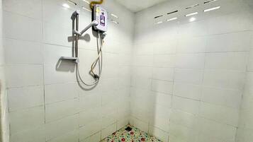A small, tiled shower area with a showerhead and control panel.