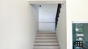 A staircase with a handrail, a sign indicating "staff only" on the door, and a window with a view of the outside. - Jira Hotel (Lampang)