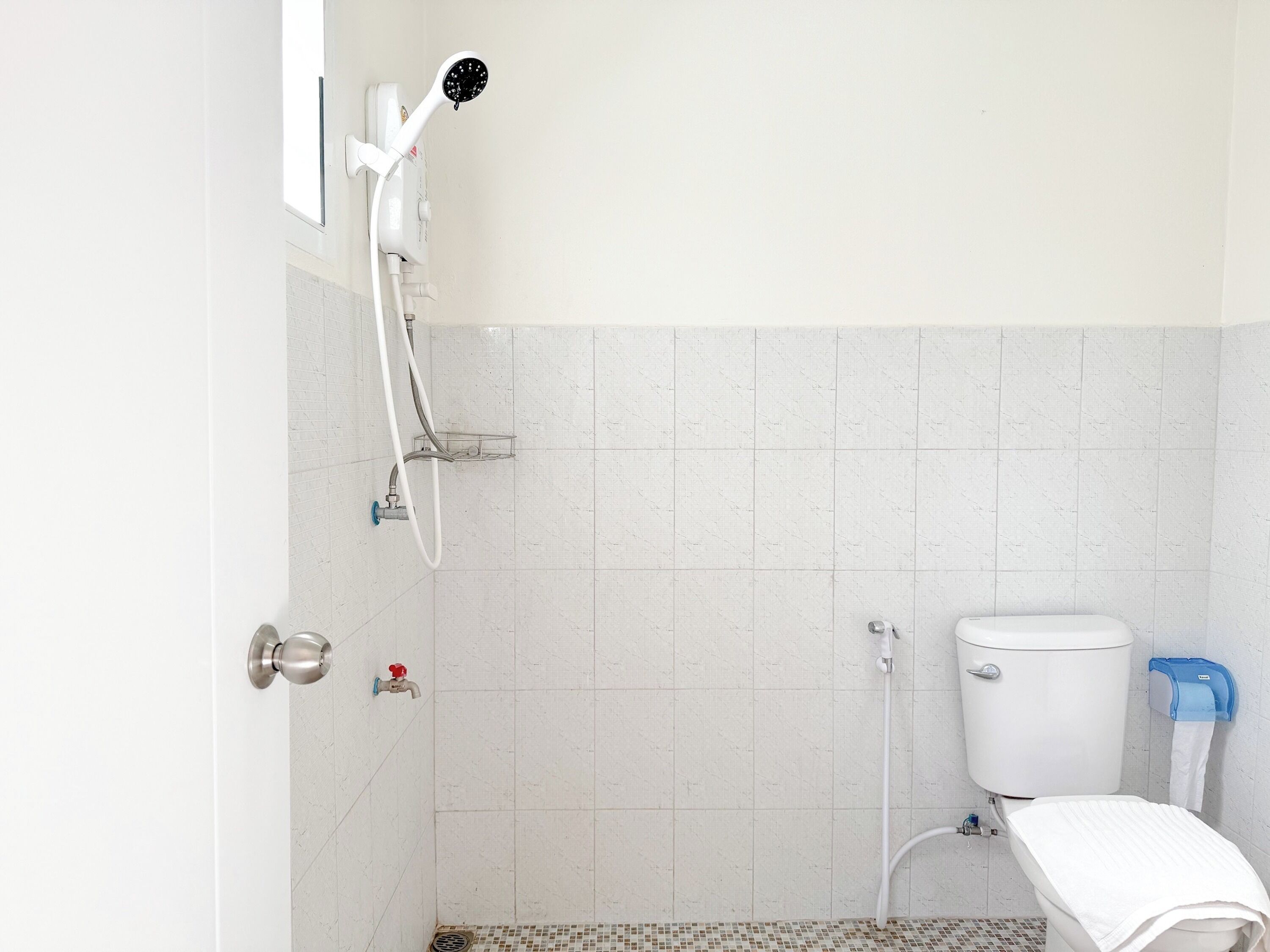 A bathroom with a shower, toilet, and a towel rack.