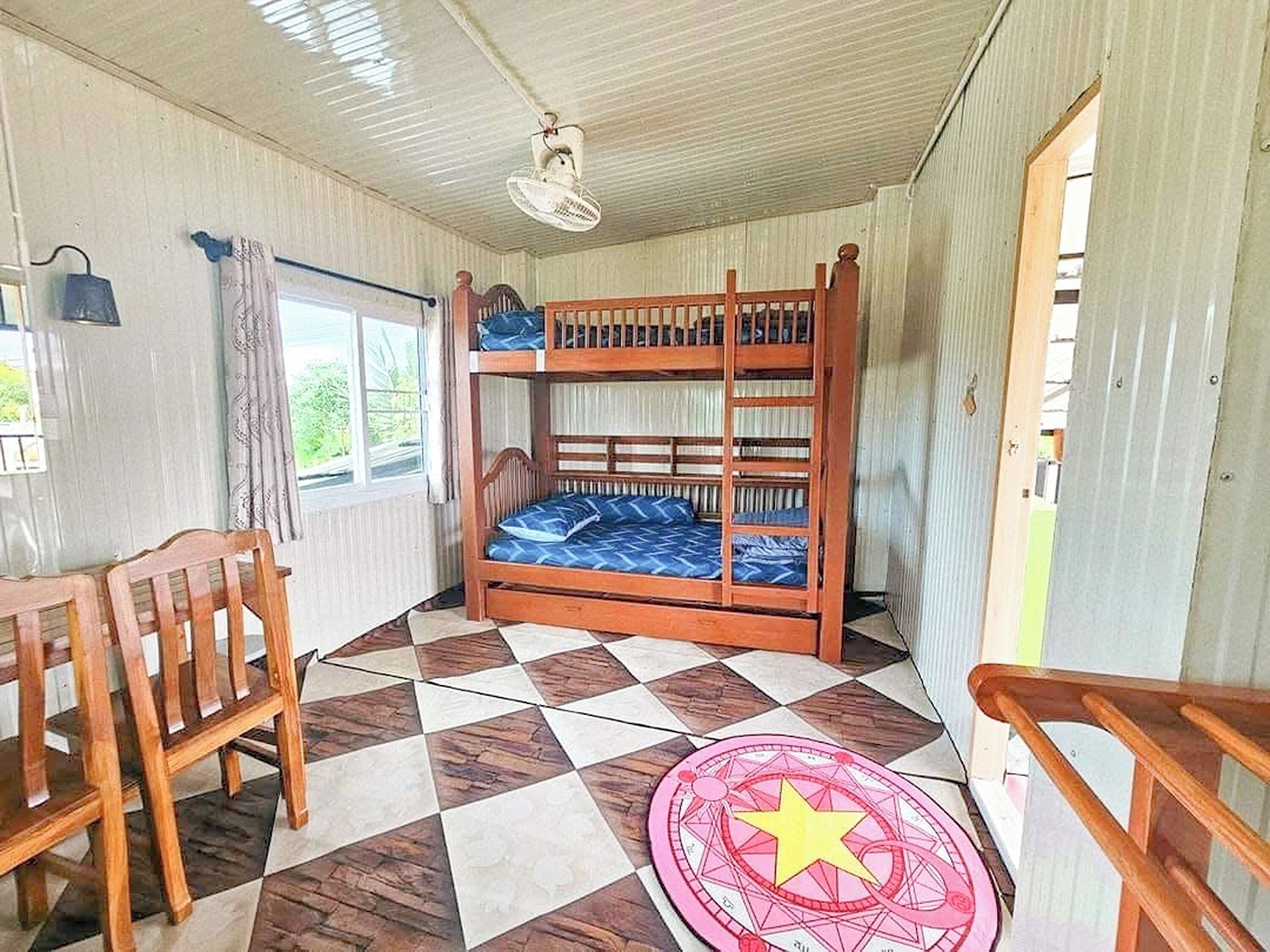 A bunk bed room with a checkered floor, a desk, and a chair.