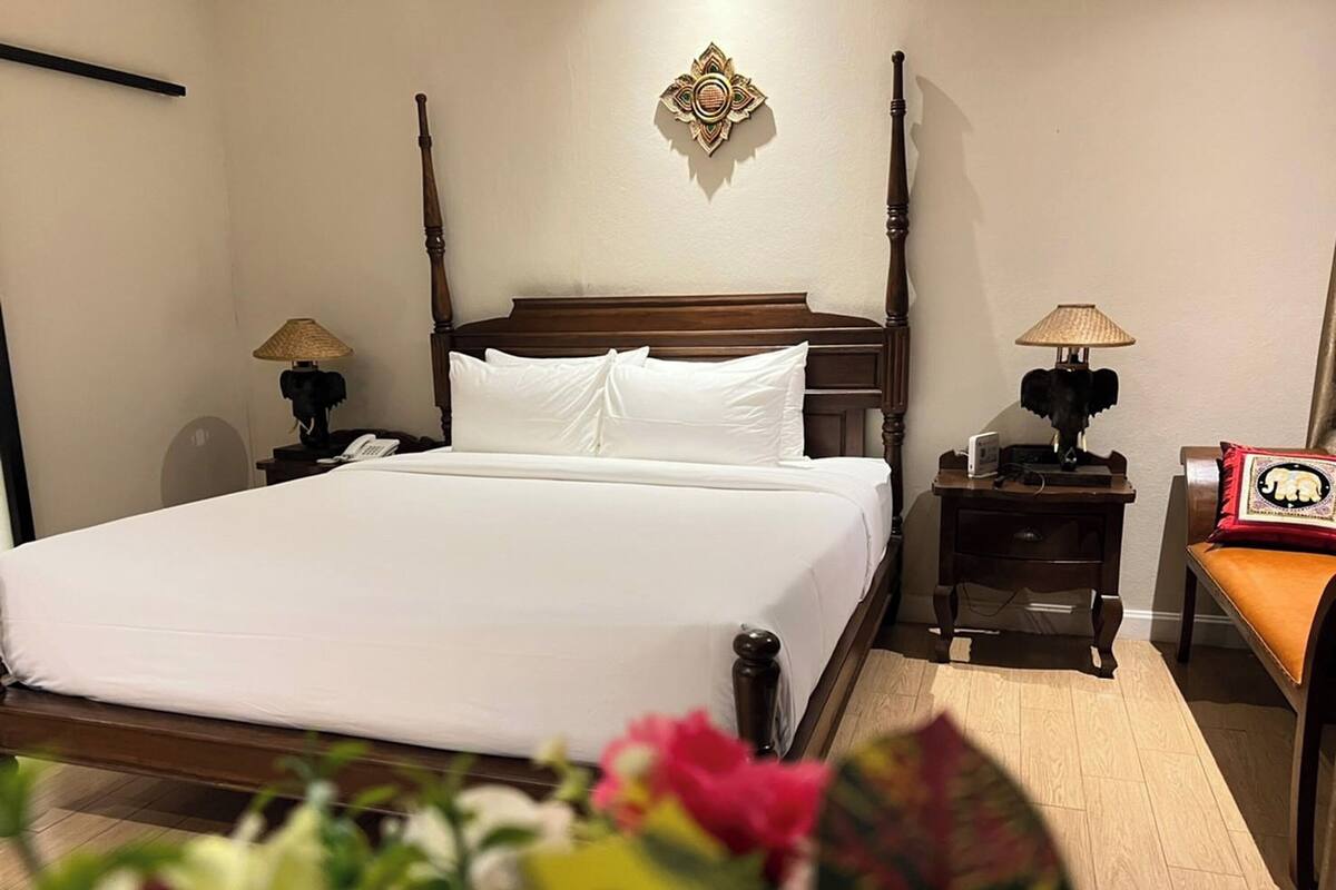 A neatly made bed with white linens in a hotel room.