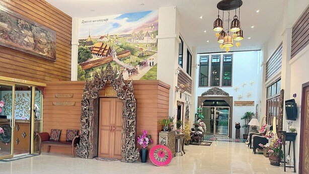 A spacious lobby with a traditional wooden reception desk, a large mural, and a modern chandelier. - Kokhaburi Hotel (Ko Kha)