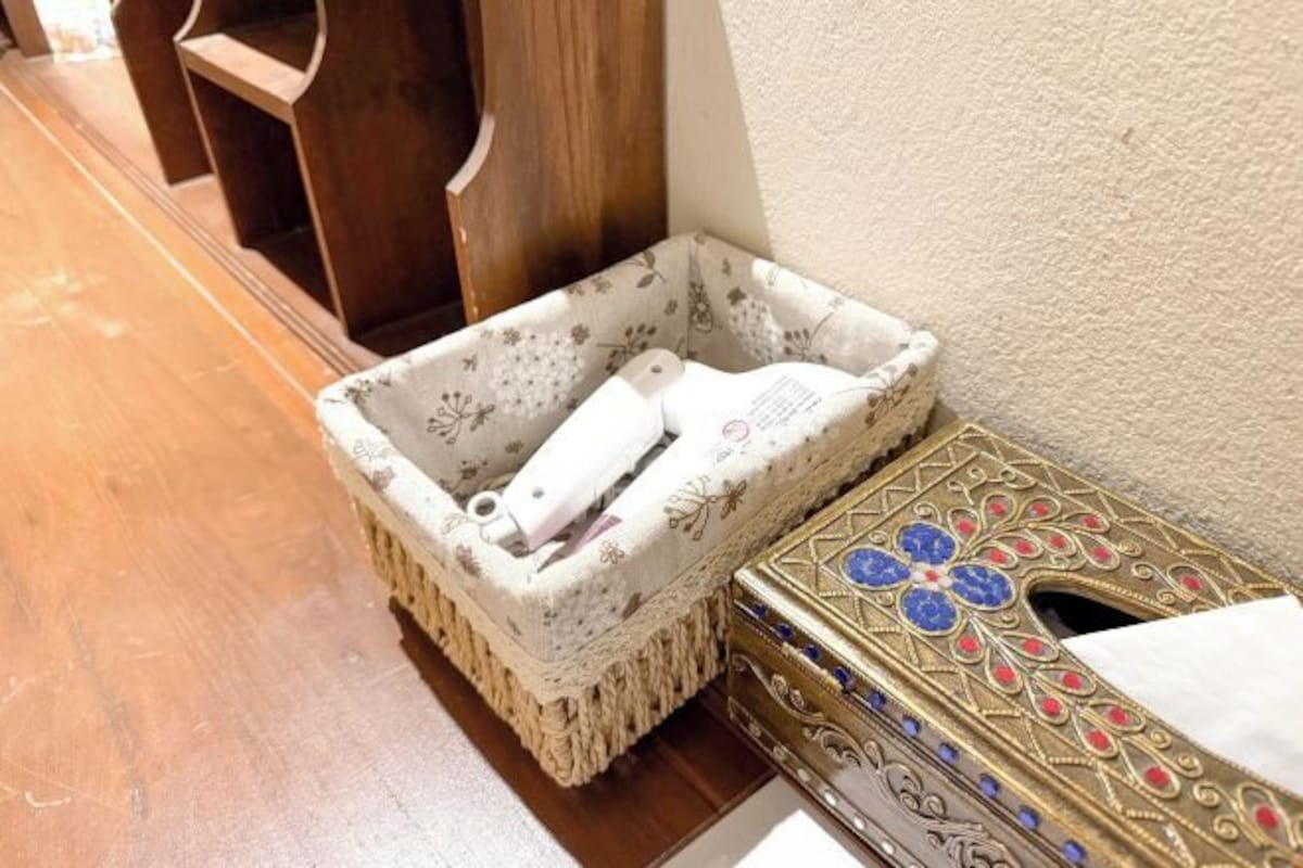 Un coin de pièce avec un plancher en bois, un mur blanc et une boîte décorative aux motifs complexes.
