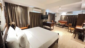 A hotel room with a large bed, a desk, a chair, a sofa, and an air conditioning unit. - Kokhaburi Hotel (Ko Kha)