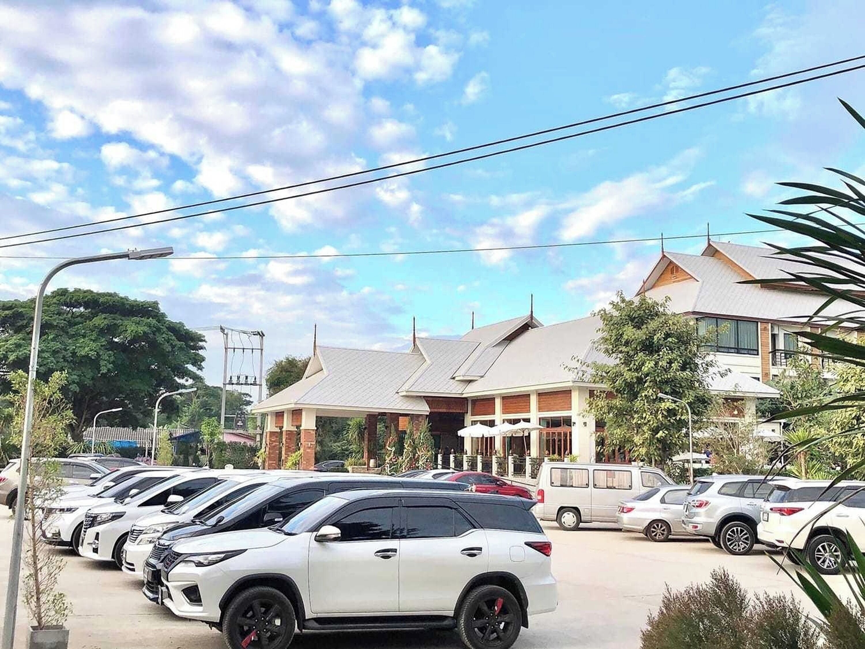 Un estacionamiento con varios SUV blancos y un edificio grande con techo inclinado al fondo.