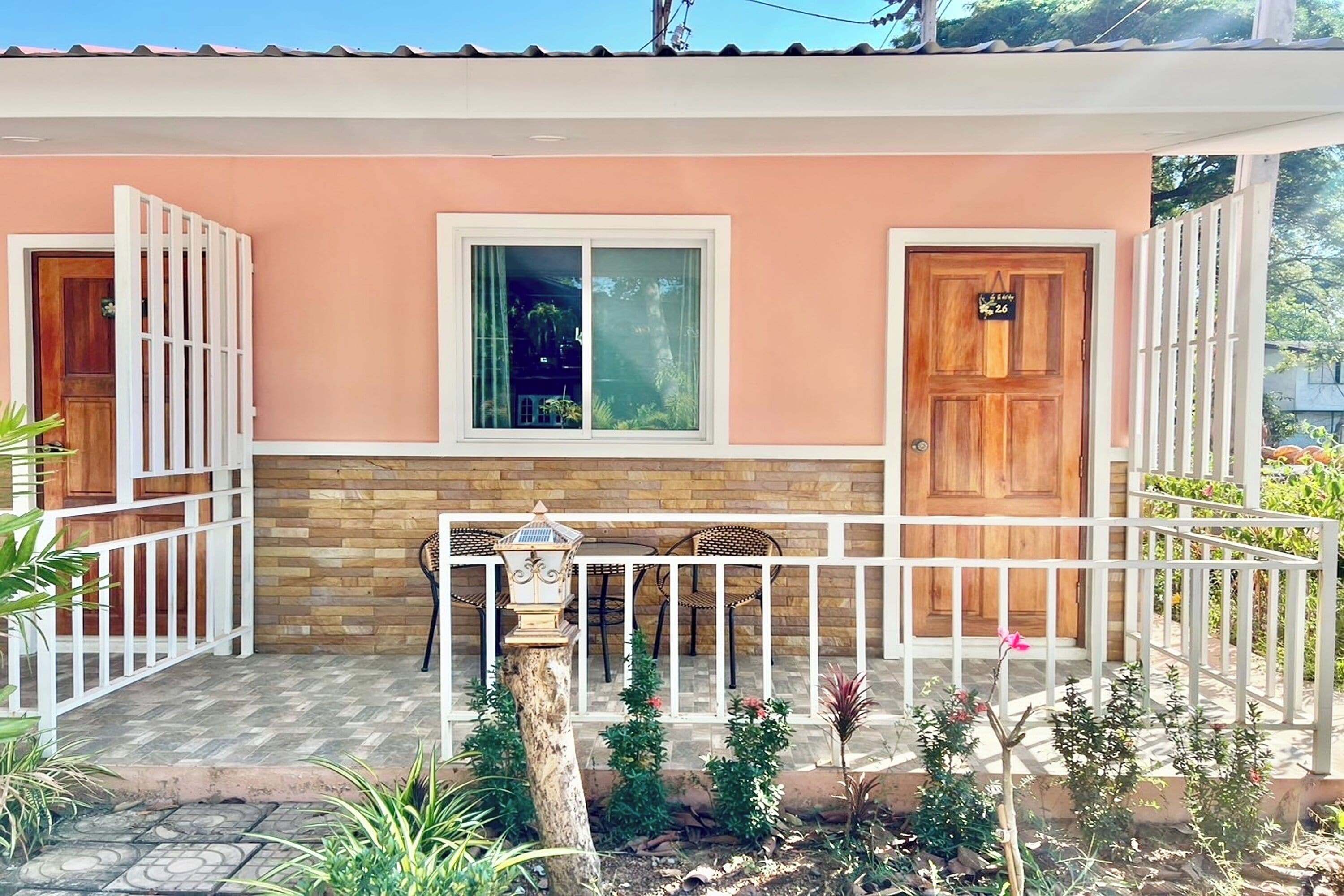 A house with a porch, a wooden door, a window, and a small garden area.