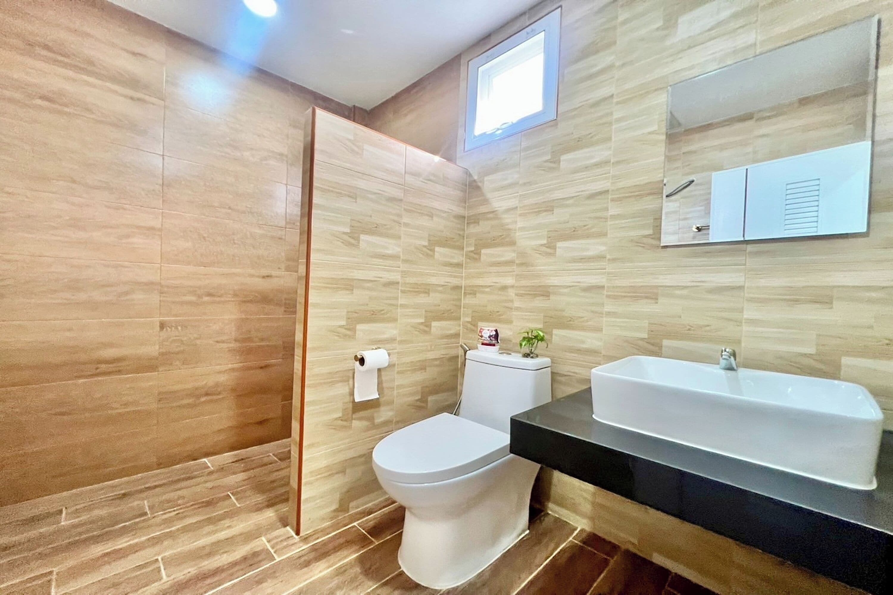 Uma casa de banho moderna com sanita, lavatório e espelho.