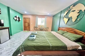 A bedroom with a bed, a desk, a chair, a small table, and a globe on the wall. - Koon Hom Apartment (Ban Dung)