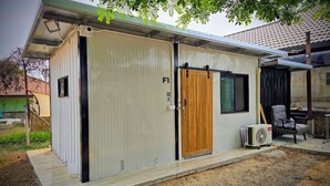 A small, single-story building with a metal exterior, a wooden door, and a small window. - Kua Car Camp (Lampang)