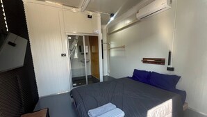 A modern hotel room with a large bed, a small desk, a walk-in closet, and a bathroom with a glass door. - Kua Car Camp (Lampang)