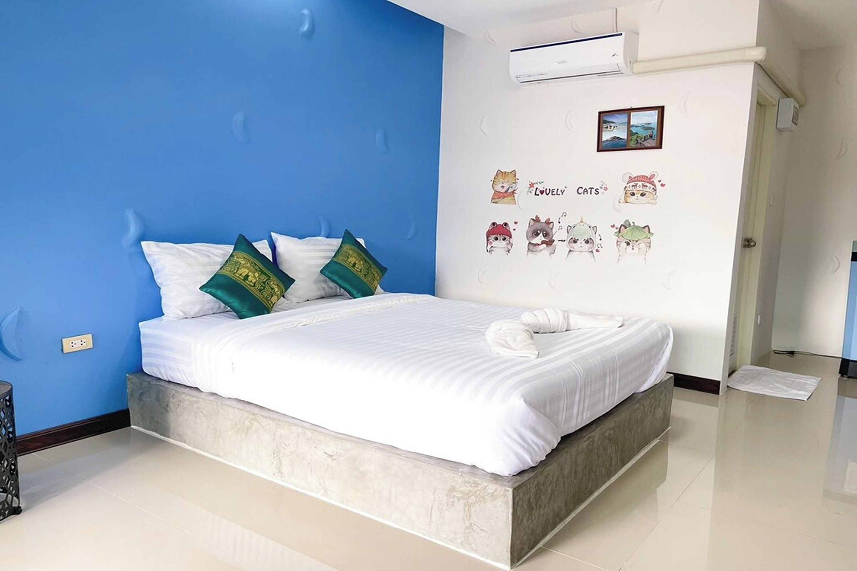 A modern bedroom with a large bed, blue walls, and decorative wall stickers.