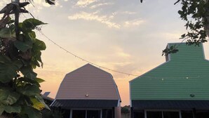 A building with a green roof and a large, light-colored barn-like structure. - Pai Tawan Resort Hotel - Pet friendly (Khon Kaen)