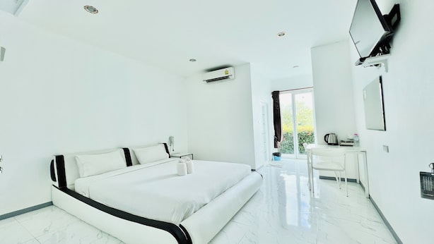 A modern bedroom with a large bed, a desk, and a TV mounted on the wall. - Parichat Bandung Hotel (Ban Dung)