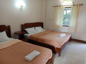 A hotel room with two single beds, each with a wooden headboard, a small bedside table, and a window with curtains. - Phumchan Place Hotel (Phayao)
