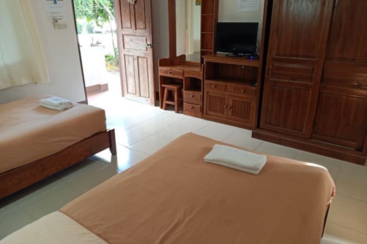 A hotel room with two beds, a desk with a chair, a television, and wooden wardrobes.