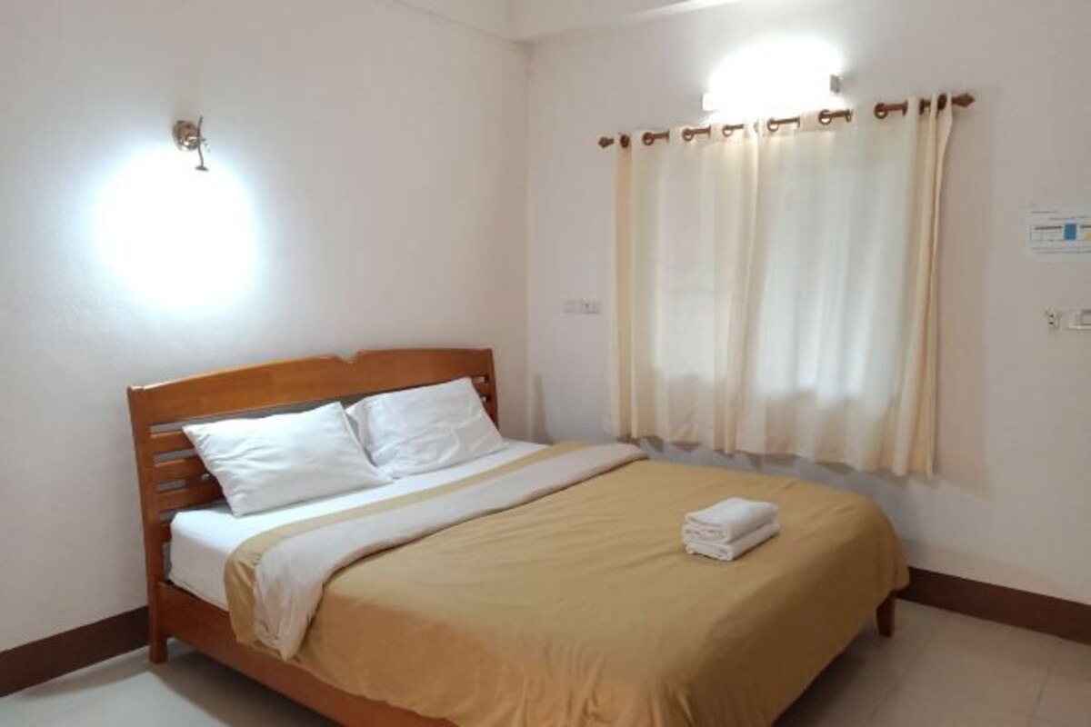 A neatly made bed with a wooden headboard, white pillows, and a beige bedspread.