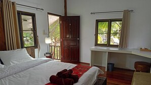 A hotel room with a large bed, a desk, and a window with curtains. - The Forest Hill Cafe & Homestay (San Sai)