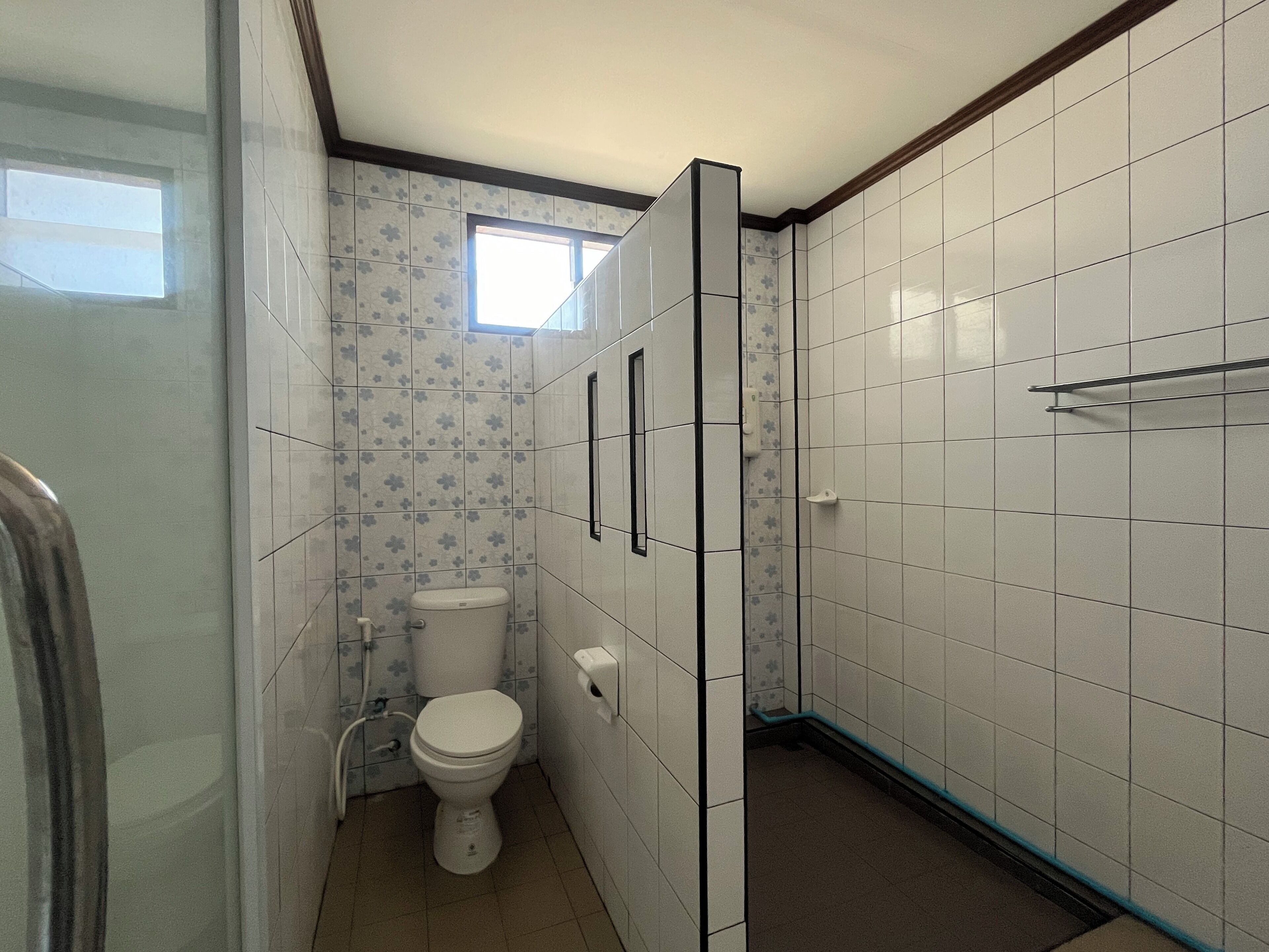 A bathroom with a toilet, a window, and tiled walls.