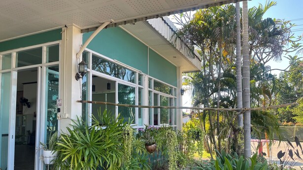 Un edificio con ventanas amplias y un porche cubierto con plantas en macetas.