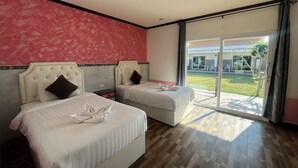 Habitación de hotel con dos camas, pared con estampado rojo y un amplio ventanal corredero que da a un espacio exterior.