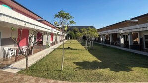 Un patio con césped, mobiliario exterior y edificios con fachadas rojas y blancas.