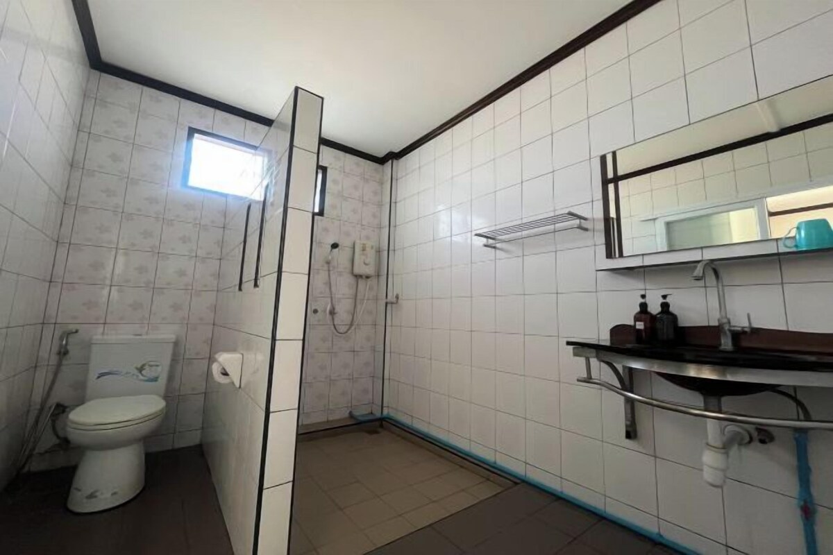 Un baño pequeño con azulejos, que incluye un inodoro, una ducha y un lavamanos con espejo.