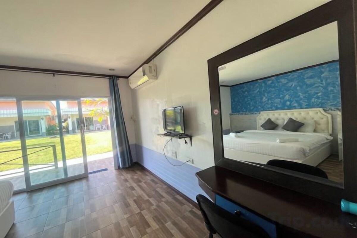 Een hotelkamer met een bed, een televisie, een bureau en een grote spiegel.