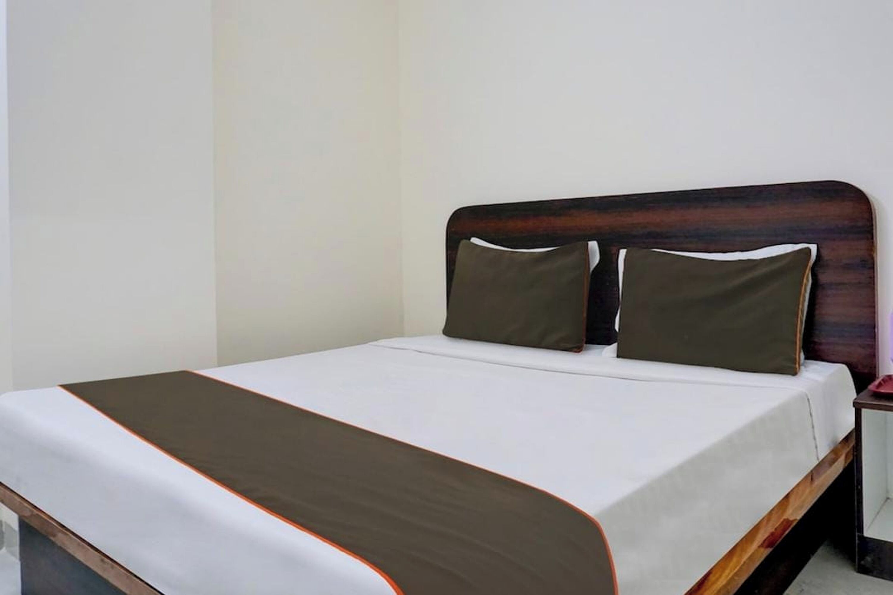 A neatly made bed with a white and brown bedspread, two pillows, and a wooden headboard.