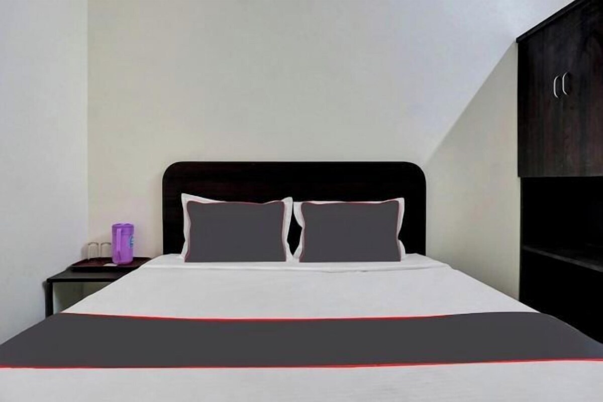 A hotel room with a bed, a nightstand, and a wardrobe.