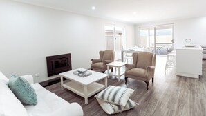 Een moderne woonkamer met een bank, fauteuils, een salontafel en een open haard.
