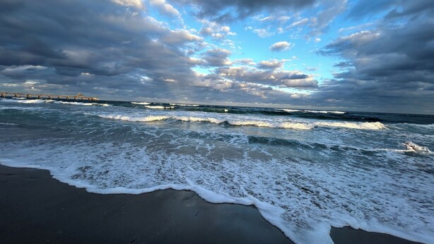 Une plage avec des vagues et un ciel nuageux.