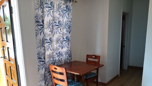 A dining area with a wooden table and chairs, a patterned curtain, and a wooden floor.
