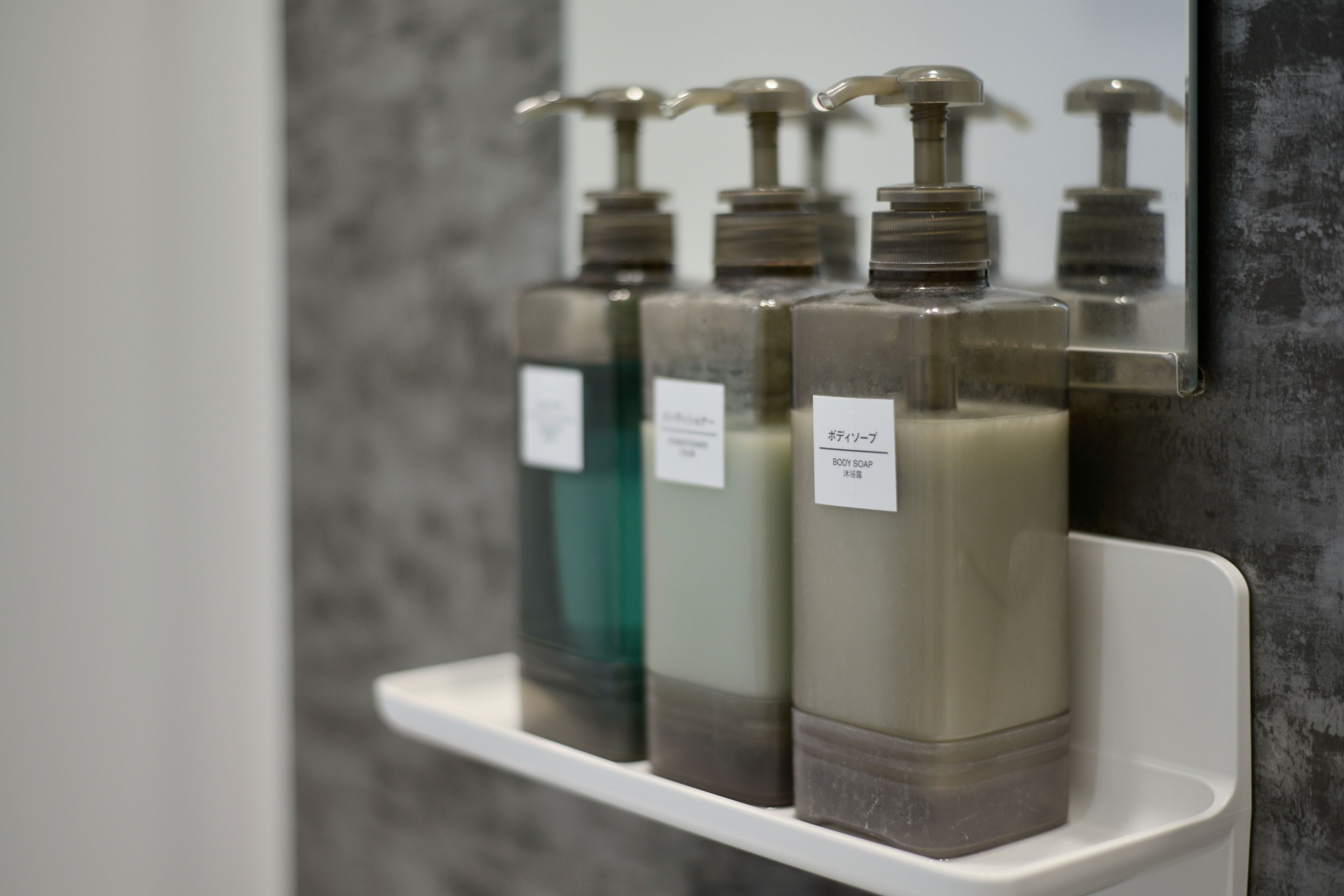 Una estantería con tres dispensadores de jabón de baño.