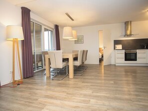 A modern kitchen with a built-in oven and a dining area with a table and chairs.