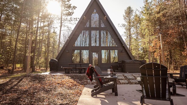 A cabin with a triangular roof, large windows, and a picnic table outside. - HOT TUB and gorgeous lake views-The Lily Pad A Frame-minutes from Dells (Wisconsin Dells)