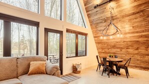 A modern interior with a wooden wall, large windows, a sofa, and a dining area. - HOT TUB and gorgeous lake views-The Lily Pad A Frame-minutes from Dells (Wisconsin Dells)