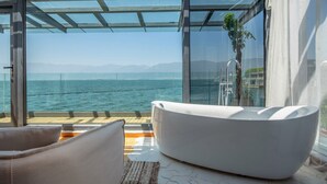 A modern bathroom with a large bathtub, a glass-enclosed window, and a view of the sea. - Dali Lanting Seaview Resort Hotel (Dali)