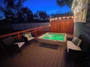 Terraza con jacuzzi, piso de madera y mobiliario exterior.