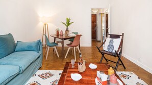 A living room with a blue sofa, a wooden coffee table, and a dining area with a table and chairs.