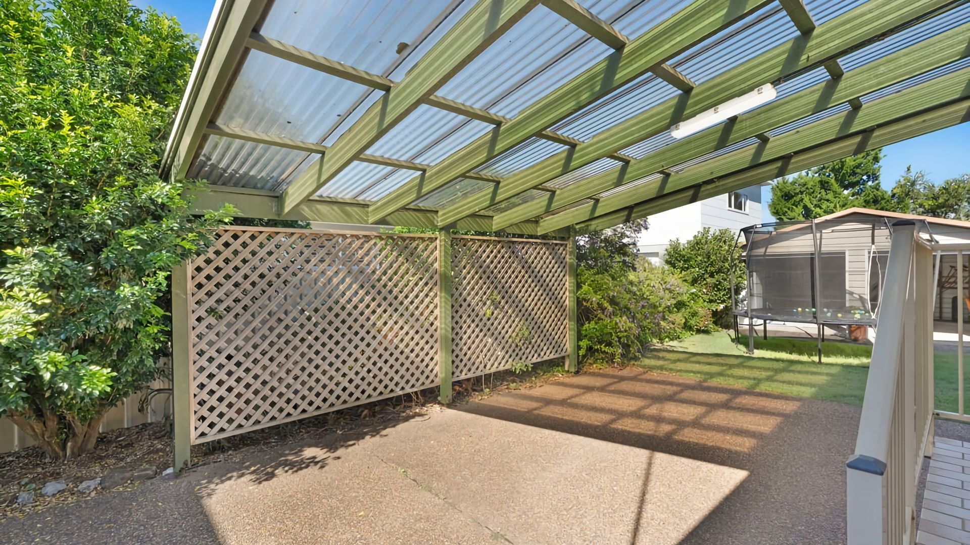 A covered patio area with a lattice fence, a small shed, and a garden.