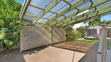 A covered patio area with a lattice fence, a small shed, and a garden.